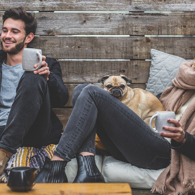 A man and woman drinking coffee with their dog
